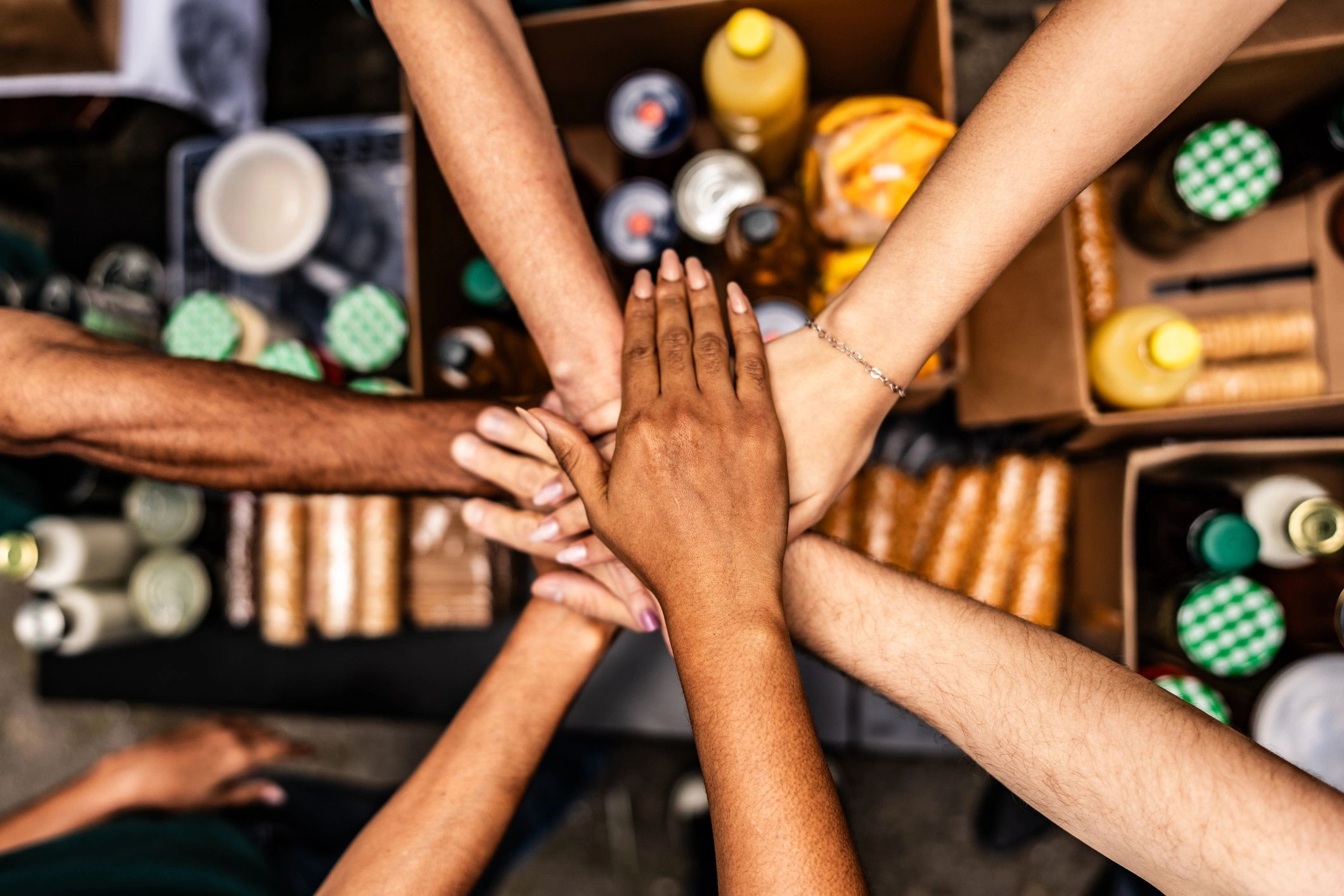 Volunteers stacking hands over donation boxes